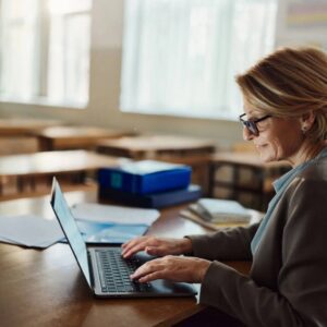 Woman using laptop in empty classroom