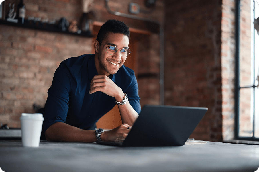Smiling man using laptop in brick-walled workspace