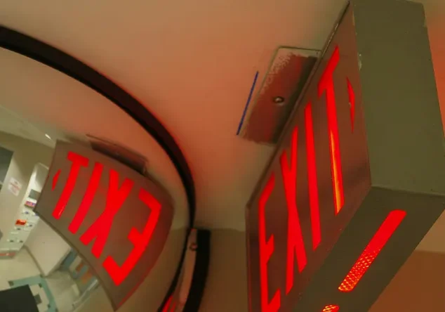 Red exit sign reflected in convex mirror