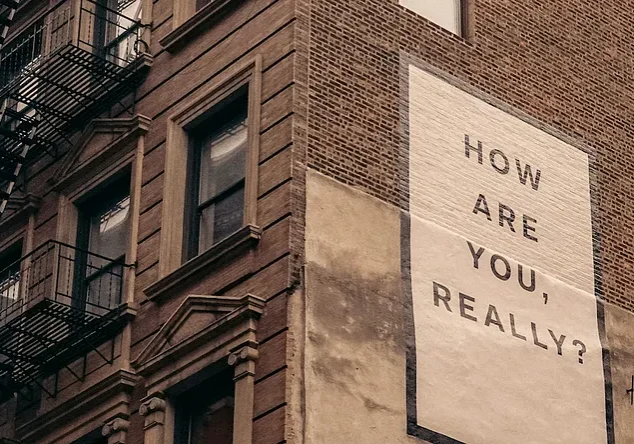 Brick building with "How are you, really?" mural