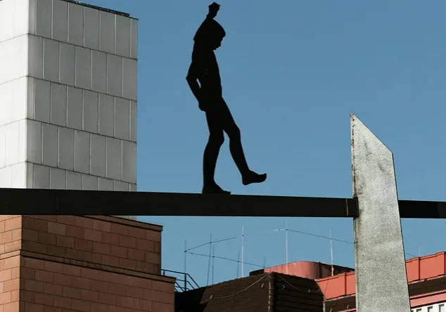 Silhouette of walking man sculpture on beam