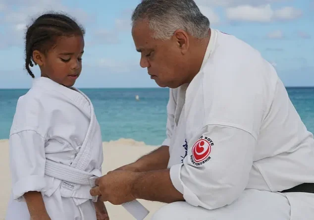 Instructor tying young martial artist's belt