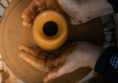 Hands shaping clay pot on pottery wheel