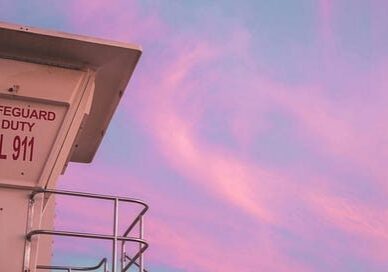 Lifeguard tower sign against pastel pink sky
